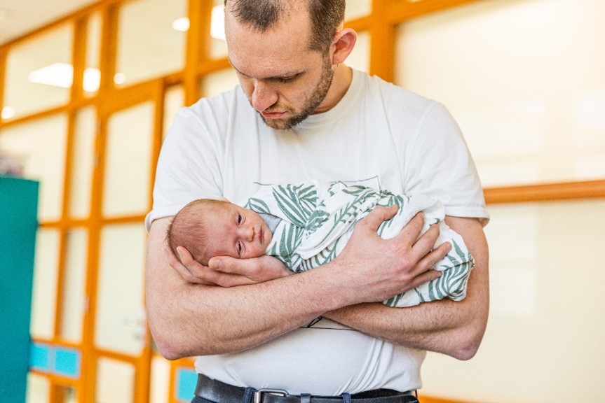 Foto Kidsgids Amsterdam. Een vader oefent met zijn pasgeboren baby tijdens een HBM-workshop.